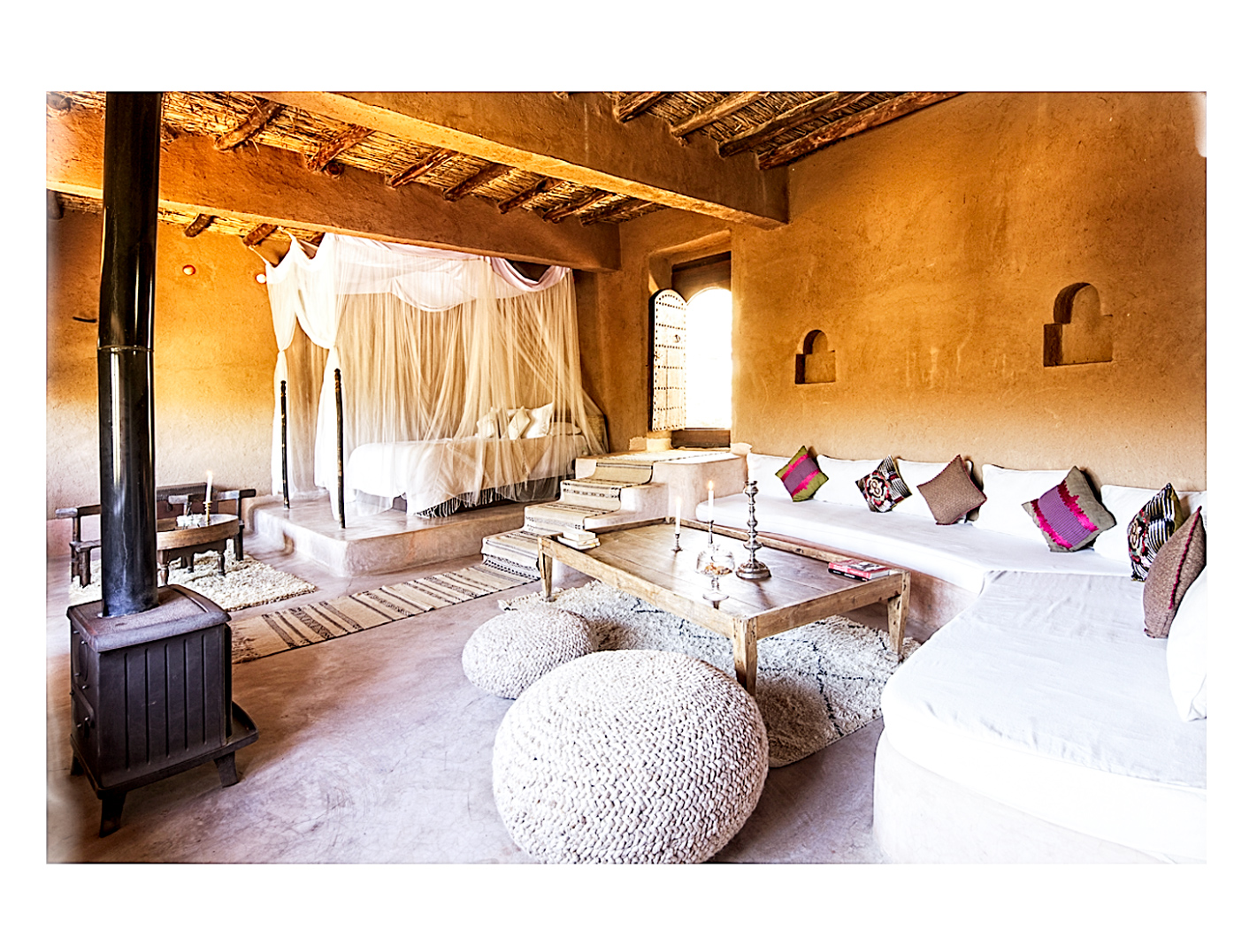 MarocCoin salon dans une chambre lodge avec canapés, poufs et une cheminée traditionnelle à La Pause, Maroc